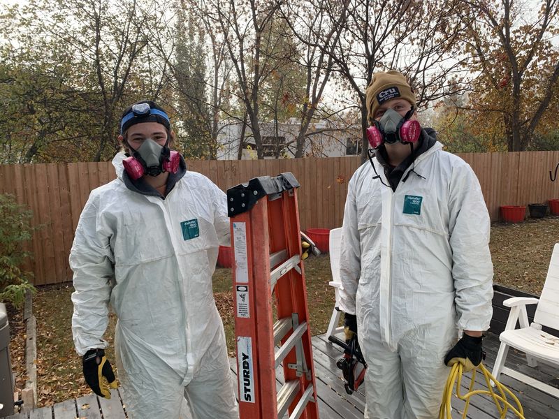 Leighton and Denim in full PPE with respirators and protective suits, ready for an attic job